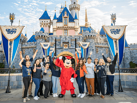 college students and mickey mouse wearing a graduation gown at disneyland 