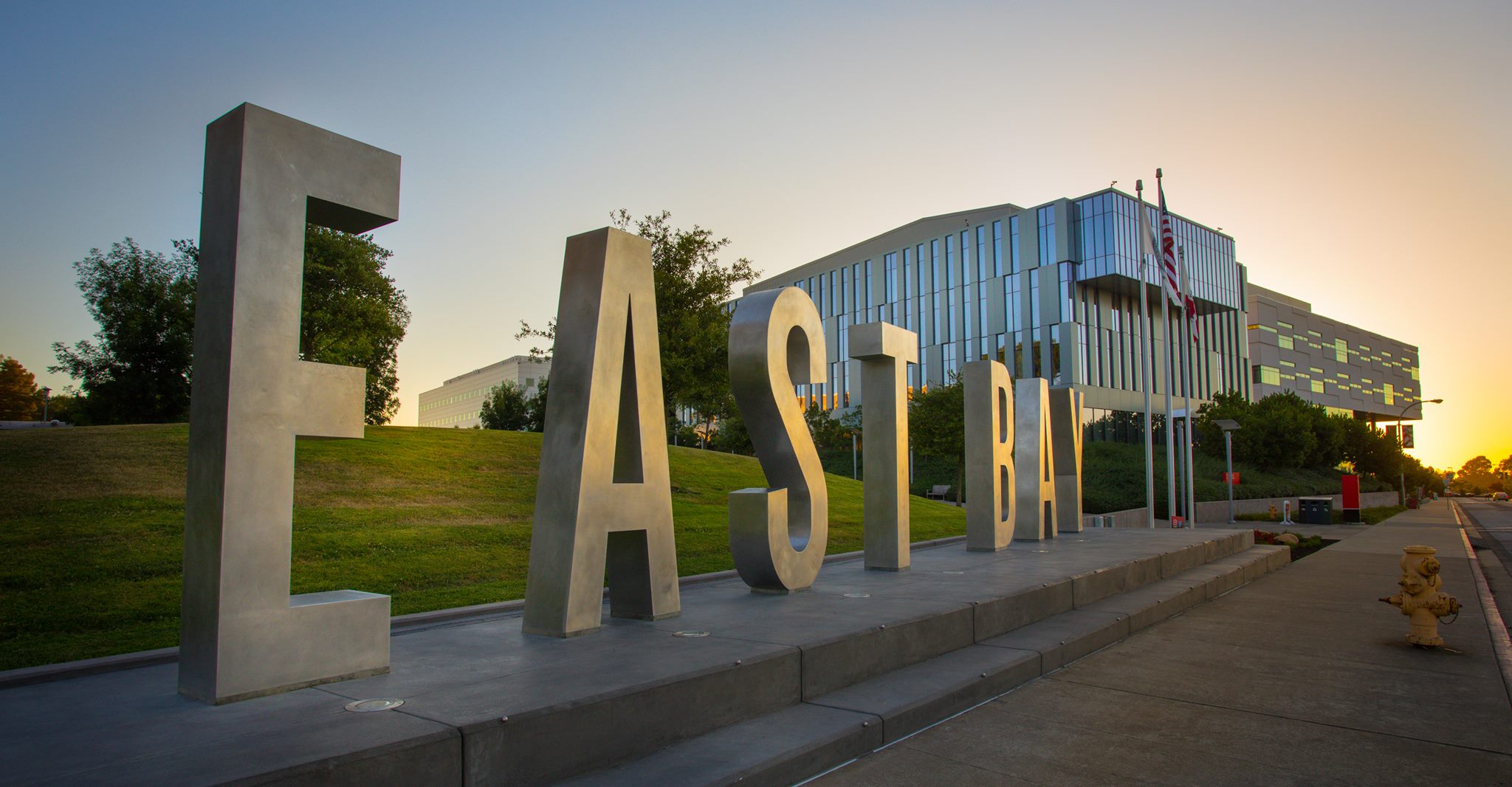A close up of giant letter that spell East Bay on the campus.
