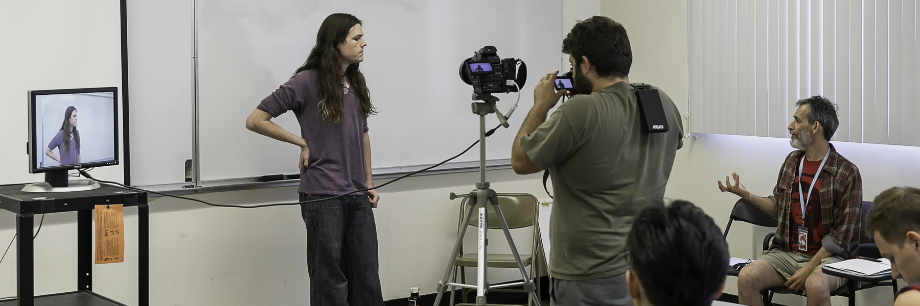 man standing  infront of digial camera in a classroom setting