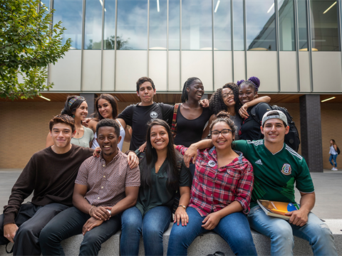 A group of diverse students smiling and sitting together.