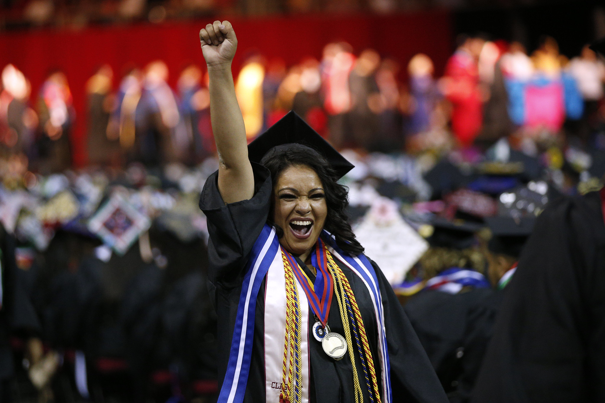 woman holding up fist during college commencement ceremony