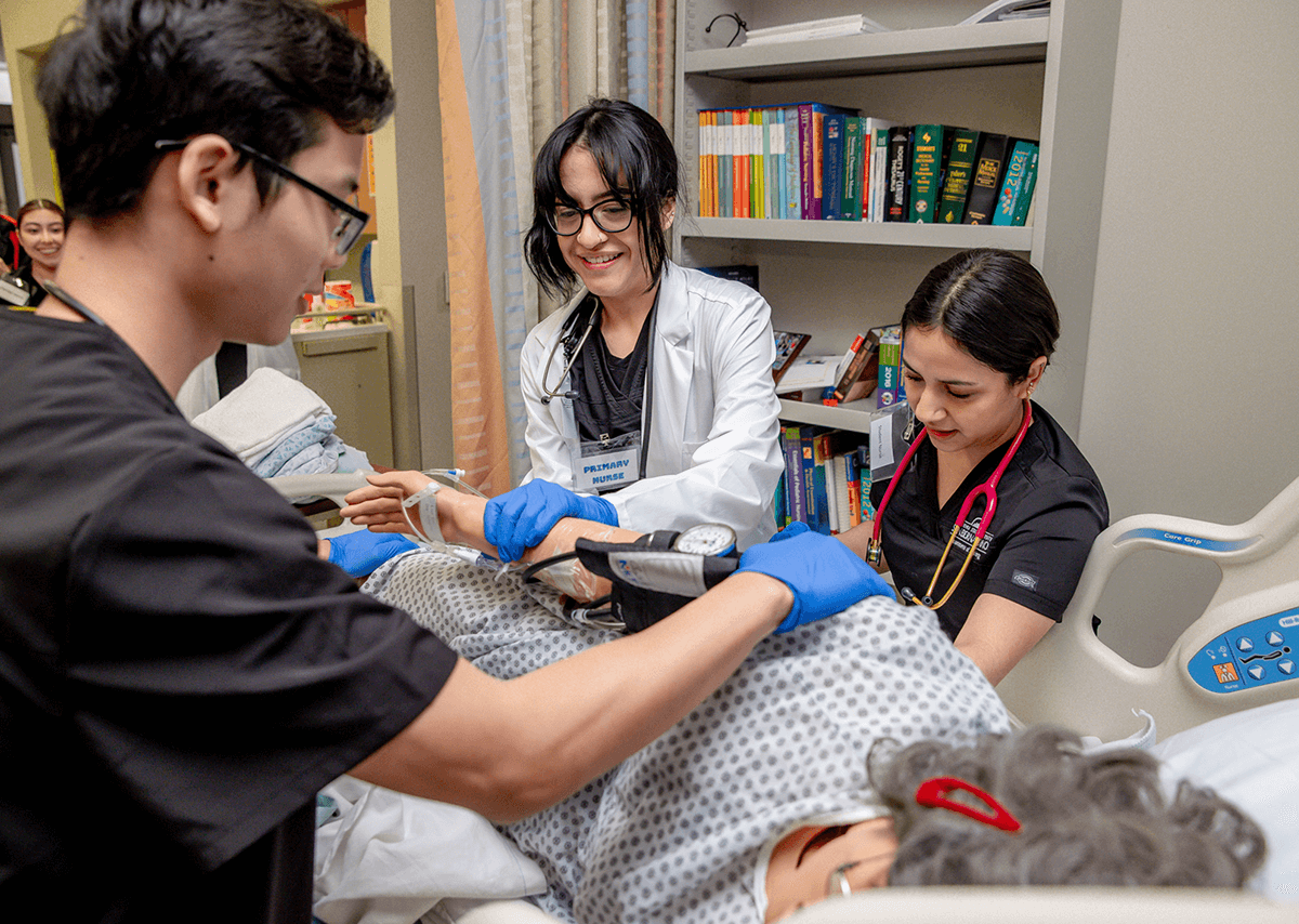 Cal State San Bernardino nursing students checking on practice patient's vitals.