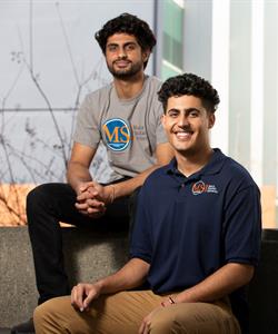Two smiling young men sitting on a couch.