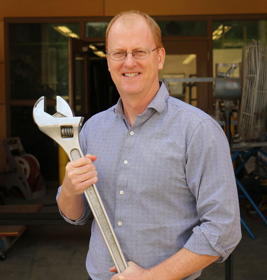 Dr. Brian Self holds an oversized wrench.