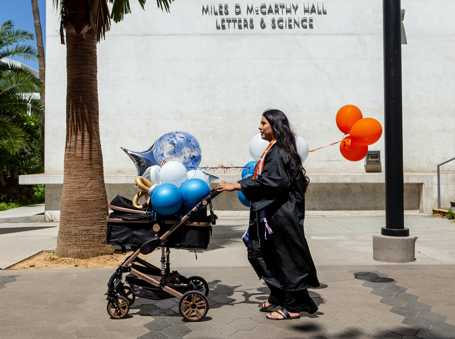 woman pushing stroller filled with ballons on a college campus