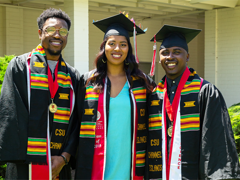 Three Black students side-by-side for a picture at graduation.