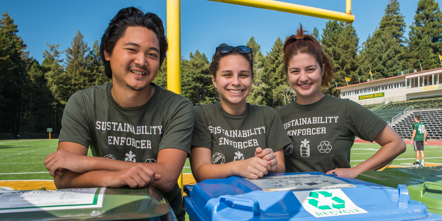 Students stand by recycling bins.