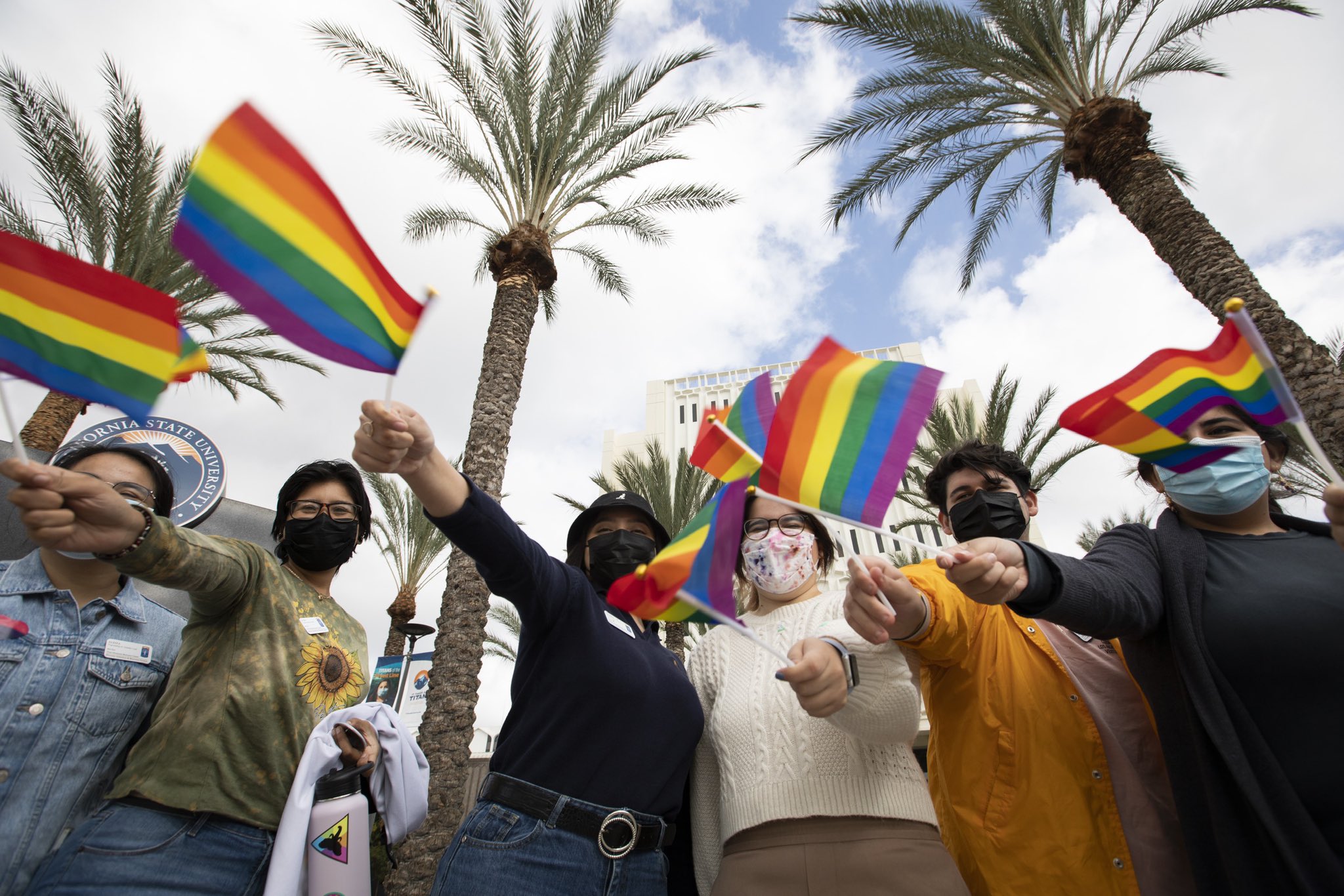students holding rainbow flags in a group on campus