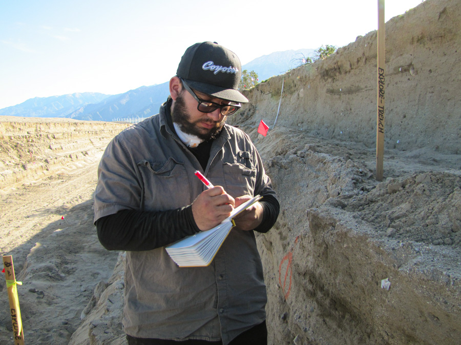 Under the direction of Dr. McGill, Bryan Castillo studies sediment layers of a 40-meter section of a trench dug along the San Andreas Fault.