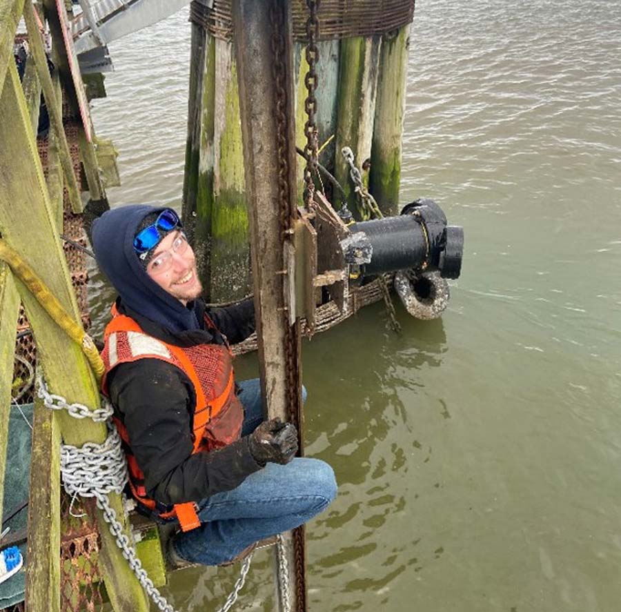 Bennett Hosselkus, oceanography/physics undergraduate student and PORTS technician, inspects a newly installed ADCP.