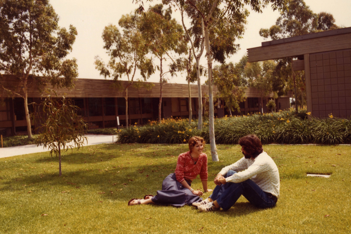 Students sit on the grass by the small college on the Dominguez Hills campus.