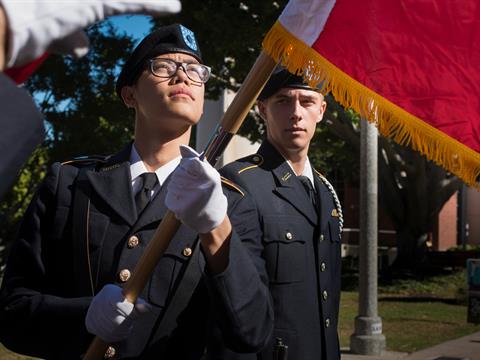 two military cadets perform a flag raising ceremony